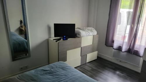 une chambre avec un lit et une télévision sur une commode dans l'établissement chez Christine, à La Celle-Saint-Cloud