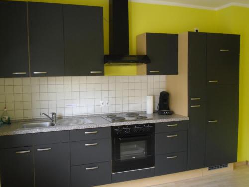 a kitchen with black cabinets and a sink at Ferienwohnung J.Weber in Hornbach