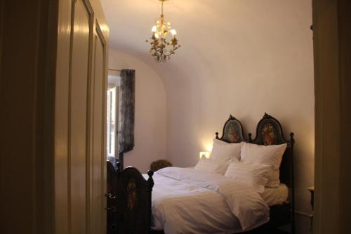 a bedroom with a bed with white sheets and a chandelier at Friciulin - guest house in Lesegno