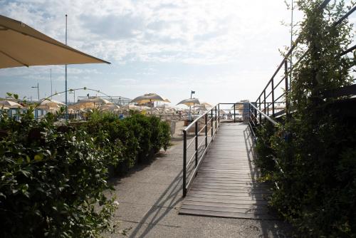 a wooden walkway leading to a beach with umbrellas at Hotel Garden Lido in Loano