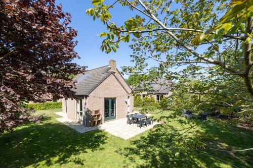 a small white house with a patio in the yard at Holiday home for the whole family in Ewijk