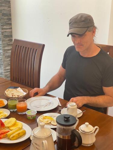 een man aan een tafel met ontbijtproducten bij Sithuka Villa Bentota in Bentota