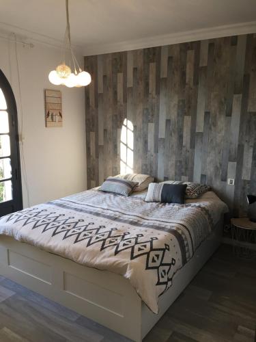 - une chambre dotée d'un grand lit avec un mur en bois dans l'établissement Villa Lunel 250 m2 -axe Montpellier-Grande Motte, à Lunel