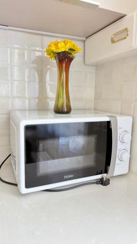 a vase with yellow flowers sitting on top of a microwave at National Stadium-Naadam Center-Tsengeldekh apartment in Ulaanbaatar