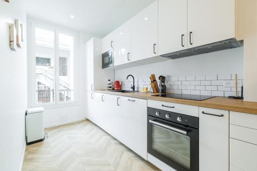 une cuisine avec des armoires blanches et un four noir dans l'établissement Large & Confort 2 Bdr Renovated, à Nice