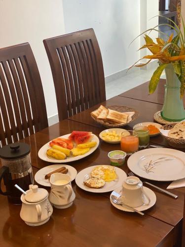 een houten tafel met borden ontbijtproducten erop bij Sithuka Villa Bentota in Bentota