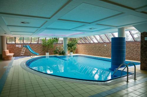 a large swimming pool with a slide in a building at Rodinný Hotel Hubert High Tatras in Vysoké Tatry