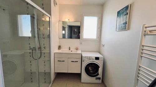 une salle de bain avec une machine à laver et un lavabo dans l'établissement Immersion marine, T2 front de mer, à Saint-Hilaire-de-Riez