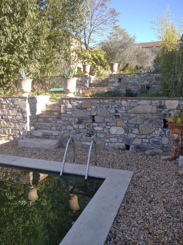 un mur en pierre et un banc dans une cour dans l'établissement La Forge 1846, à Servas