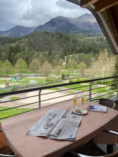 a table with a newspaper and two glasses of wine at MONTE MISONE 2.0 in Comano Terme