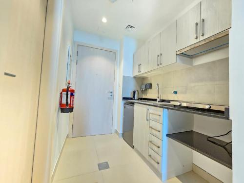 a kitchen with white cabinets and a white door at Studio KCA - 609 in Abu Dhabi