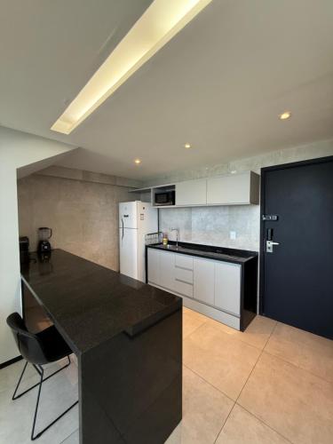 a kitchen with a black counter top and a refrigerator at Beach Flats Barra Home Stay By Flatbpaiva in Recife