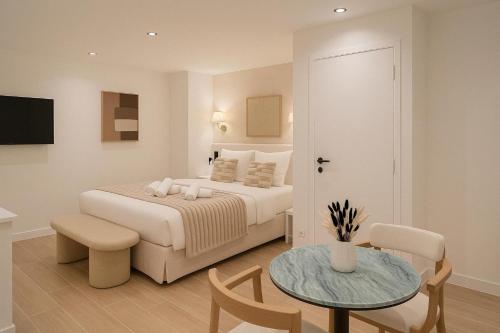 - une chambre blanche avec un lit, une table et un sidx de table dans l'établissement Chic Studio Charonne, Haut-Marais, à Paris