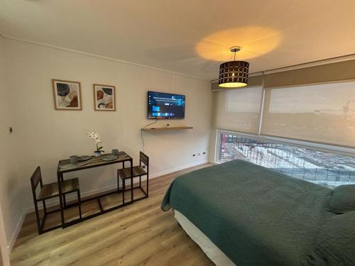 a bedroom with a bed and a table and a television at Moderno Estudio en Osorno Full Equipado in Osorno