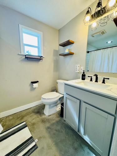 a bathroom with a toilet and a sink and a mirror at Big home in the heart of Sulphur in Sulphur