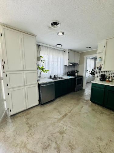 a large kitchen with green cabinets and a white door at Big home in the heart of Sulphur in Sulphur