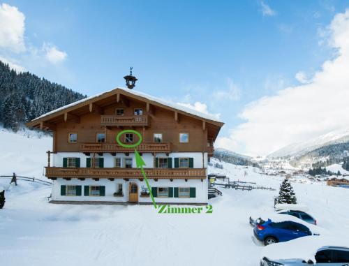 a building in the snow with cars parked around it at Riederhof in Leogang