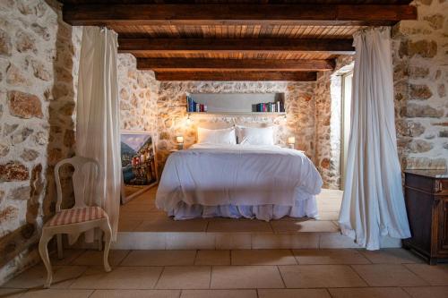 a bedroom with a white bed in a stone building at Paradise cottage in Vinišće