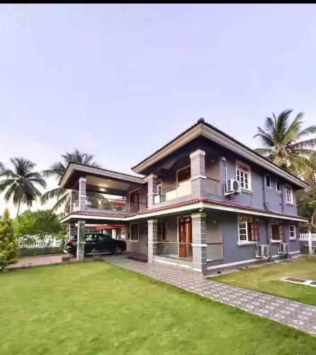 a house with a lawn in front of it at Sun-kissed Emerald 4 bedroom villa in Betalbatim