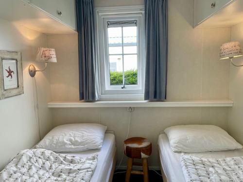 two beds in a room with a window at Chalet Zilt Ameland in Hollum