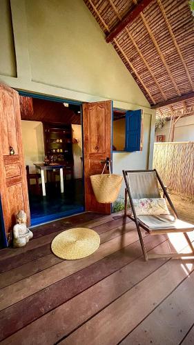 a room with a chair on a wooden floor at Ravenala Lodge, Bungalow et Maison Ile aux Nattes in Ile aux Nattes