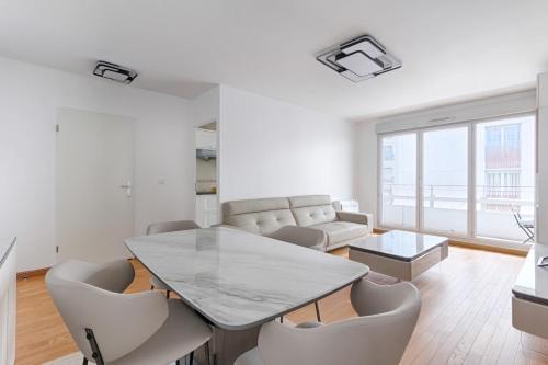 un salon blanc avec une table et des chaises dans l'établissement Saint Denis Leon Nozal Magnifique Apartment 5P, à Saint-Denis