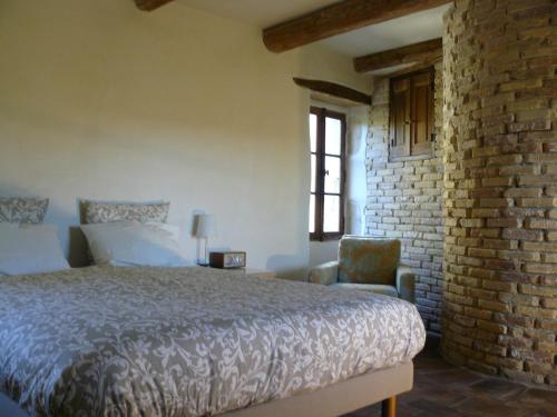 - une chambre avec un lit, une chaise et un mur en briques dans l'établissement Charming House with Courtyard Garden and Views, à La Celle-sous-Gouzon
