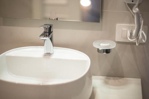 a bathroom with a white sink and a faucet at Leone Camere D'autore - Rooftop Prince Centro Storico in Naples