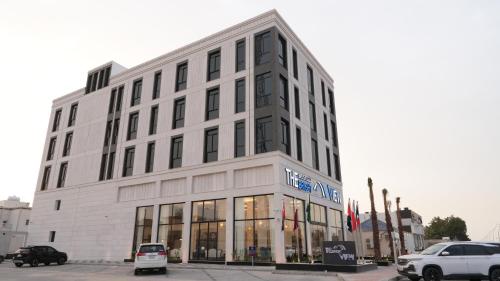 a large white building with cars parked in front of it at The bright View hotel in Al Khafji