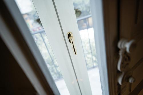 a door with a brass handle next to a window at Leone Camere D'autore - Rooftop Prince Centro Storico in Naples