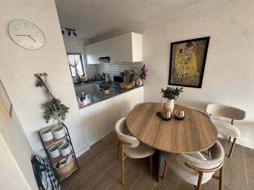 a kitchen and dining room with a wooden table and chairs at Spacious Beach Apartment with Sea & Ocean View in Cape Town