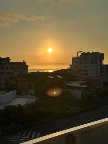 a sunset from the balcony of a building at Spacious Beach Apartment with Sea & Ocean View in Cape Town