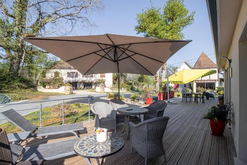 a patio with a table and chairs and an umbrella at Gite le Pic Epeiche in Sarlat-la-Canéda