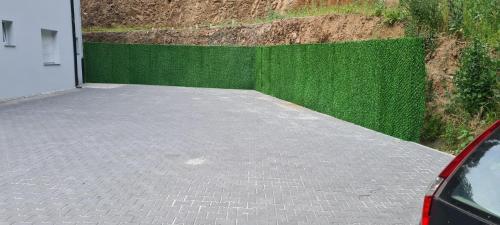 a parking lot next to a green fence at Apartmani Banjski Biser in Jošanička Banja