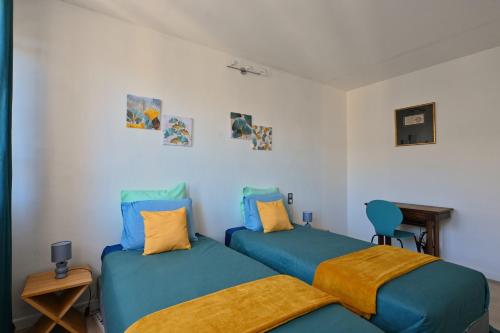 - 2 lits dans une chambre avec des oreillers bleus et jaunes dans l'établissement L'authentique - Hyper centre - Belle terrasse !, à Béziers