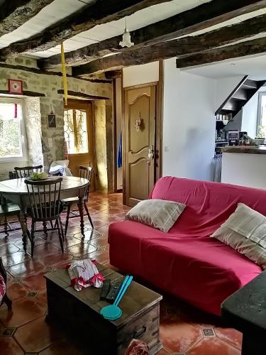un salon avec un canapé rouge et une table dans l'établissement Gîte Petit gouffre d'amour, à Padirac