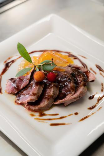 a white plate with a piece of meat with fruit at Locanda di Pietracupa in Tavarnelle in Val di Pesa