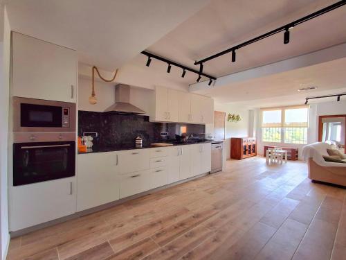 een grote keuken met witte kasten en een woonkamer bij Can Pairot in Pujals dels Cavallers