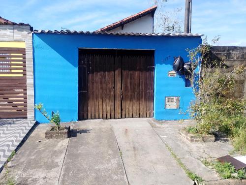 a blue building with a large wooden door at Sua paz está aqui in Mongaguá