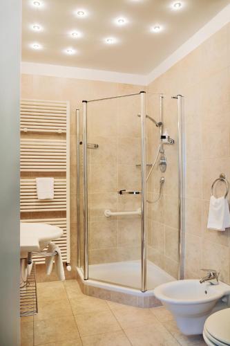 a bathroom with a shower and a toilet and a sink at Hotel Sonnenhof in Merano