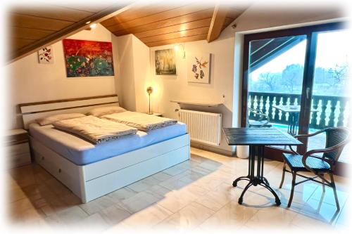 a bedroom with a bed and a table and a window at Villa Galerie in Hohenwart