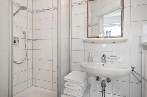 a white bathroom with a sink and a shower at Hotel Garni Vitamari in Wasserburg am Bodensee