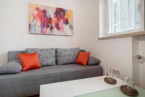 a living room with a gray couch with orange pillows at Hotel Garni Vitamari in Wasserburg am Bodensee