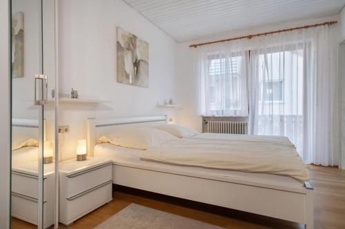 a white bedroom with a large bed and a window at Hotel Garni Vitamari in Wasserburg am Bodensee