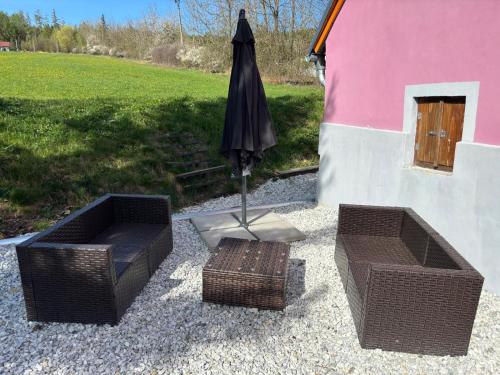 a patio with two wicker chairs and an umbrella at Šumava apartmán U Kočiček in Strašice