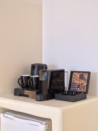 a shelf with three coffee cups and two televisions at Marjay Boutique in Parikia
