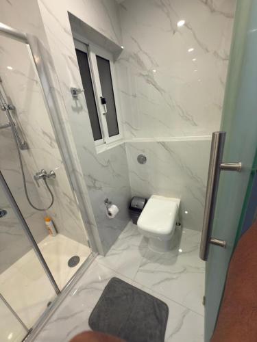 a white bathroom with a shower and a toilet at The Urban Suites in Il-Gżira