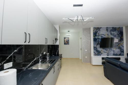 a kitchen with white cabinets and black counter tops at Sara apartment in Vlorë