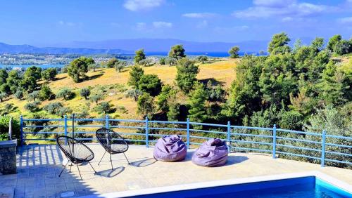 a patio with two chairs and a swimming pool at Seaview Villa with Pool for 6 in Porto Heli
