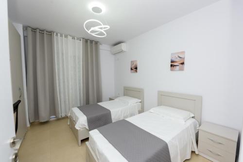 two beds in a room with white and gray at Sara apartment in Vlorë